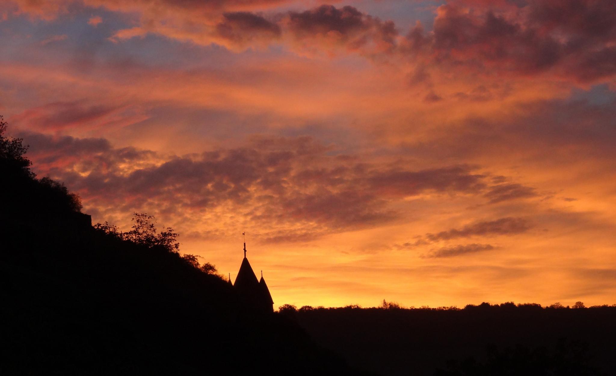 Zu sehen ist die Silhouette des Glockenturms Kobern vor rotem Abendhimmel