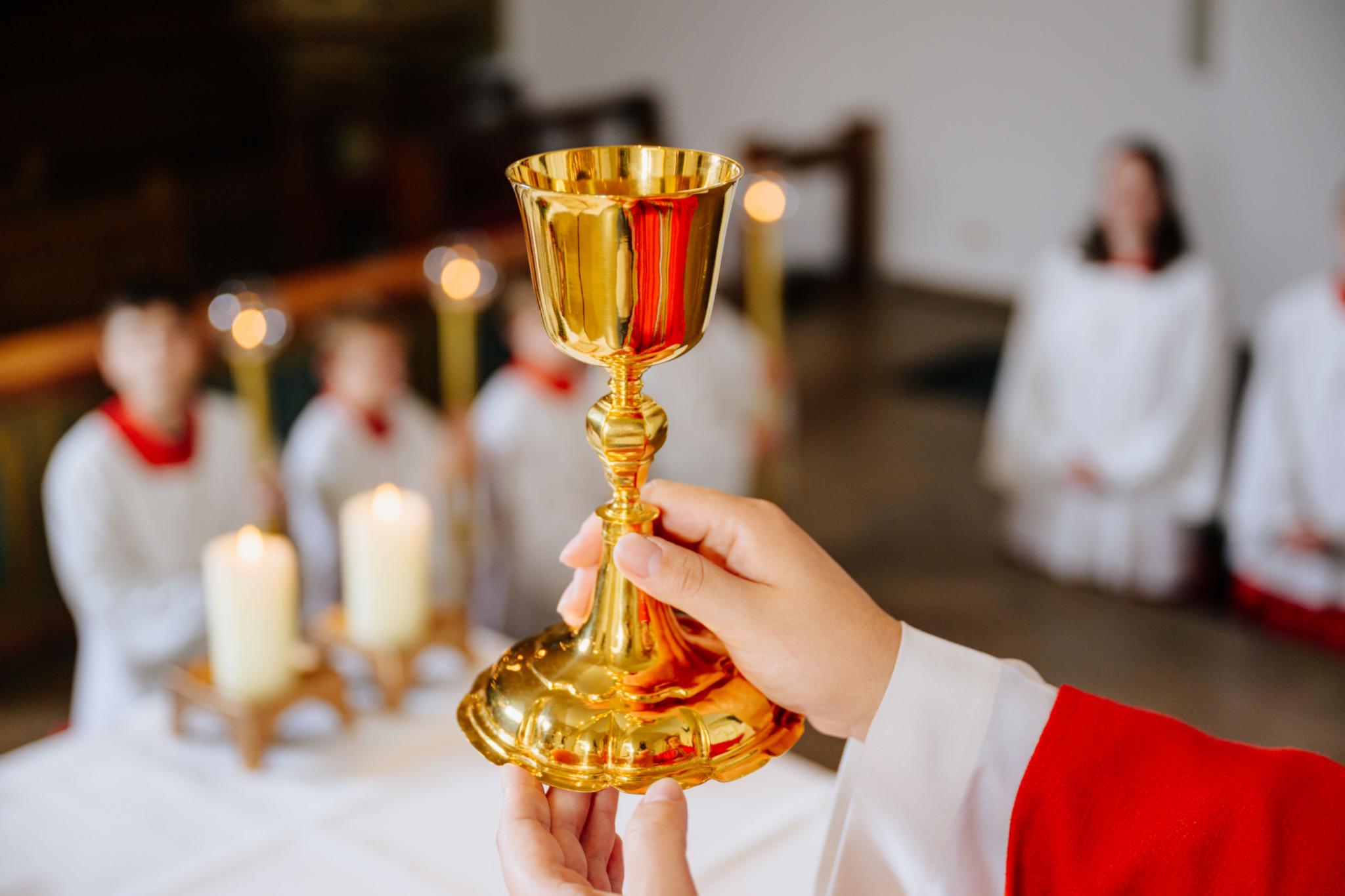 Ein Priester hält einen Kelch zur Wandlung in den Händen.